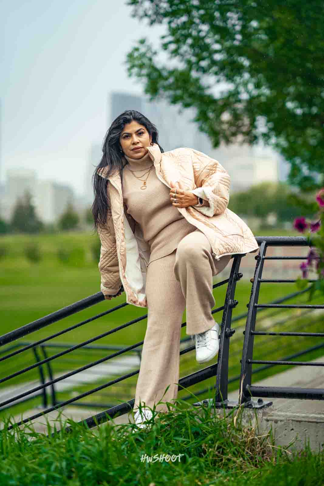 Woman in beige outfit posing beside a tree