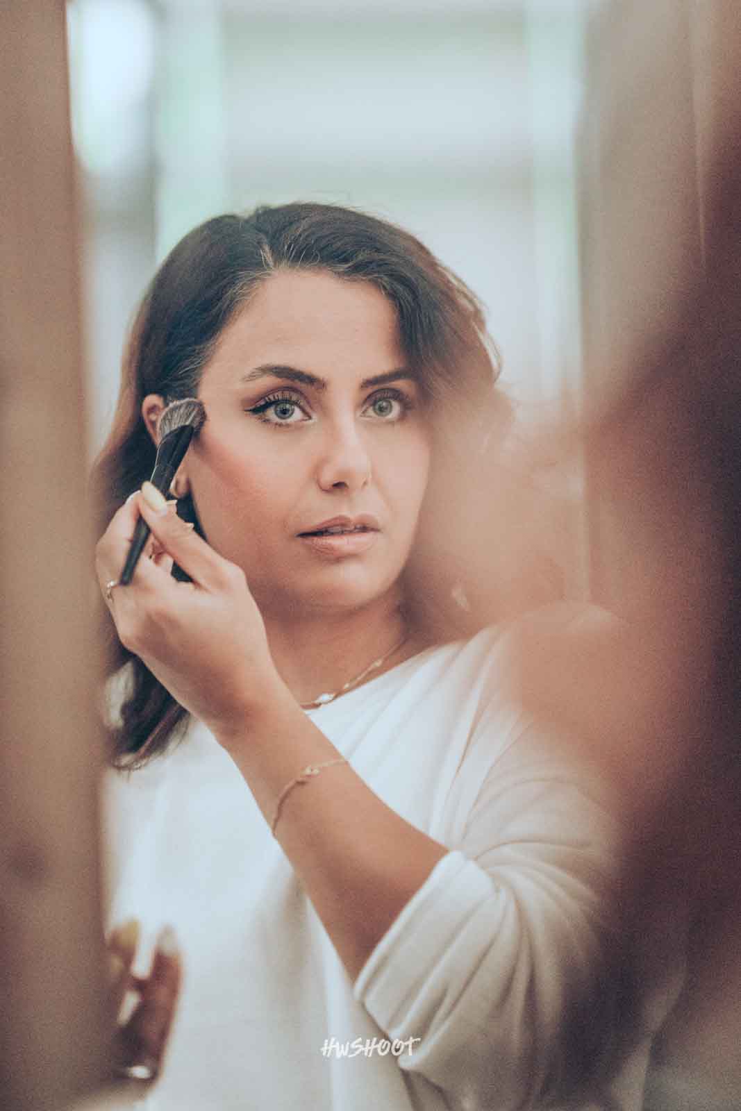 Woman applying makeup during Bella Bella by Daniela backstage session