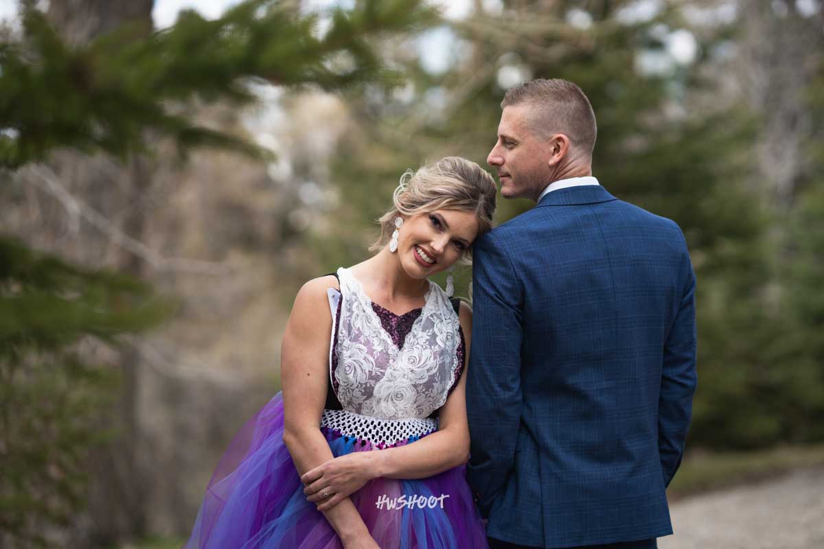 Couple posing together in a park surrounded by trees